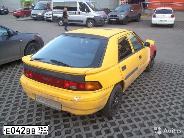 Фото автомобиля MAZDA 323, 1993 — госномер К917РР799. Цвет: МНОГОЦВЕТНЫЙ