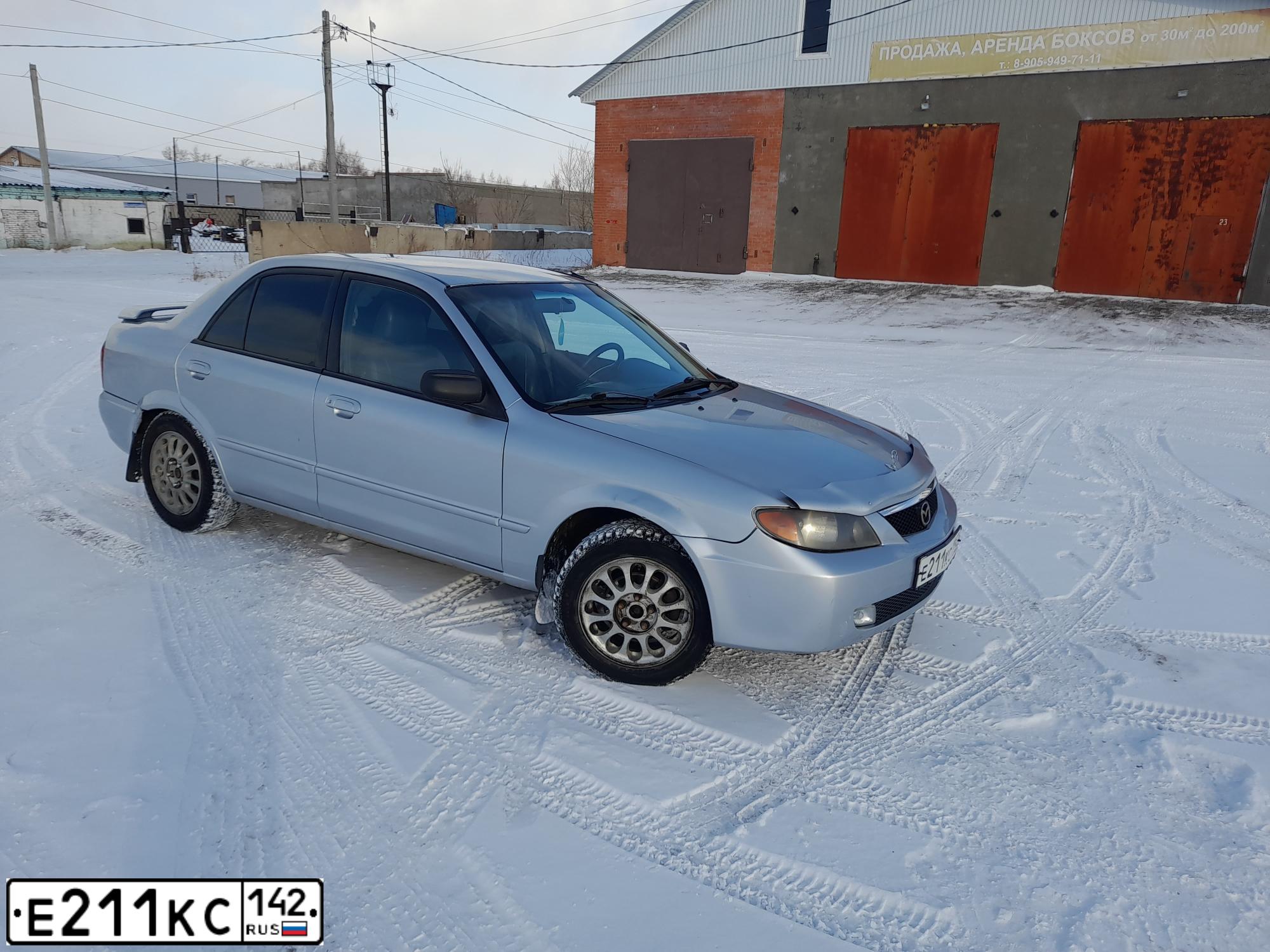 Фото автомобиля MAZDA PROTEGE, 2001 — госномер Е211КС142. Цвет: СЕРЕБРИСТЫЙ
