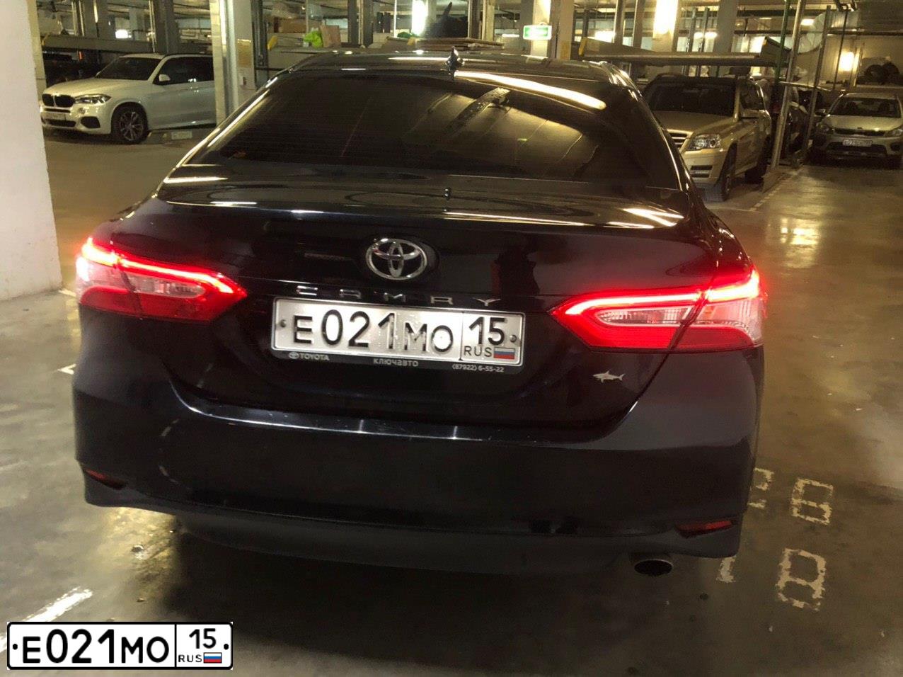 Фото автомобиля TOYOTA CAMRY, 2018 — госномер Е021МО15. Цвет: ЧЕРНЫЙ МЕТАЛЛИК