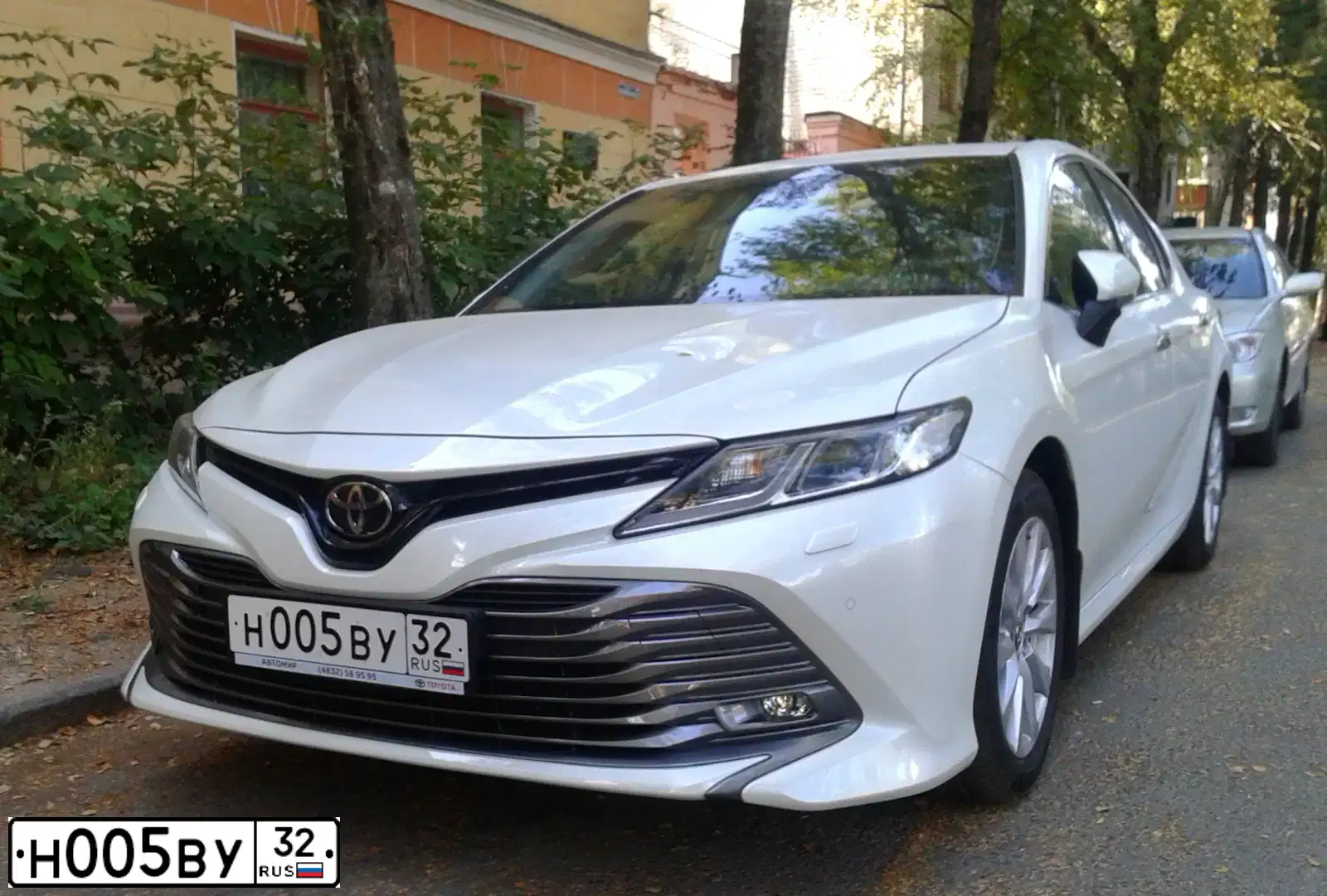 Фото автомобиля TOYOTA CAMRY, 2018 — госномер Н005ВУ32. Цвет: БЕЛЫЙ ПЕРЛАМУТР