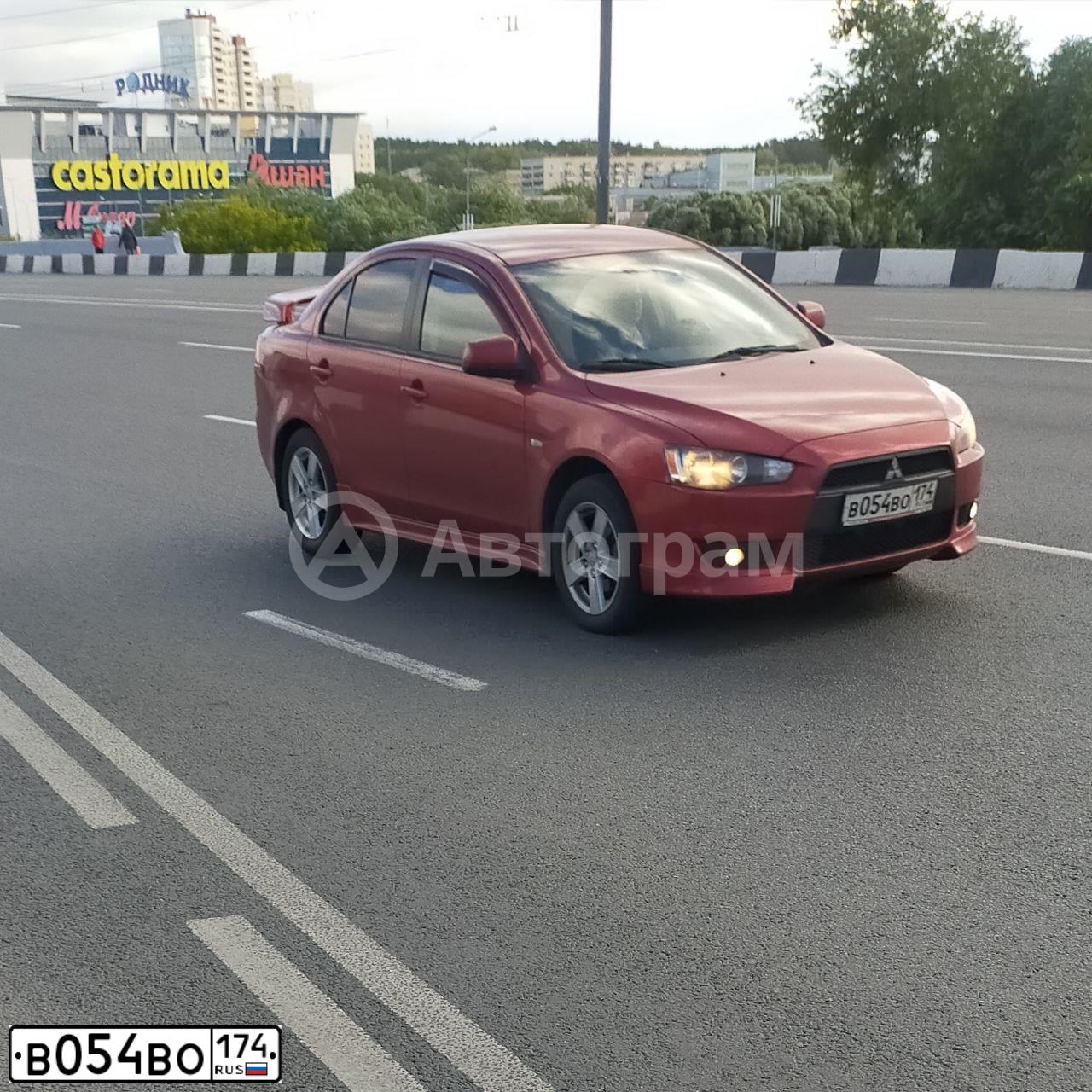 Фото автомобиля MITSUBISHI LANCER, 2008 — госномер В054ВО174. Цвет: КРАСНЫЙ