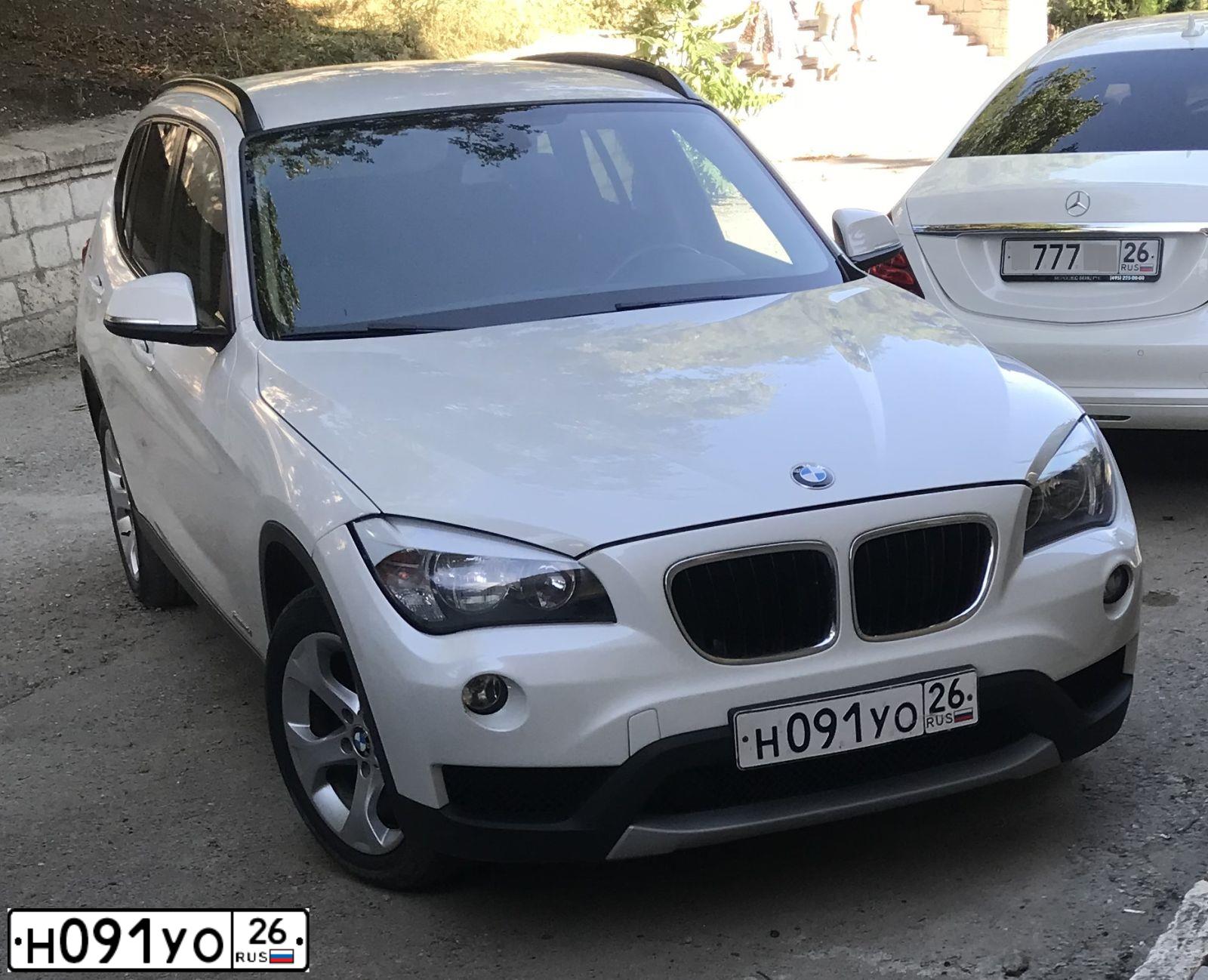Фото автомобиля BMW X1, 2012 — госномер Н091УО26. Цвет: БЕЛЫЙ МЕТАЛЛИК